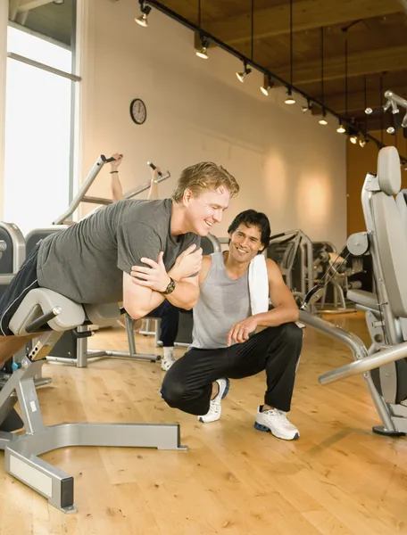 Trainer helping man exercise in health club