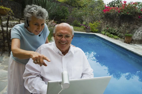 Senior couple looking at web camera on laptop