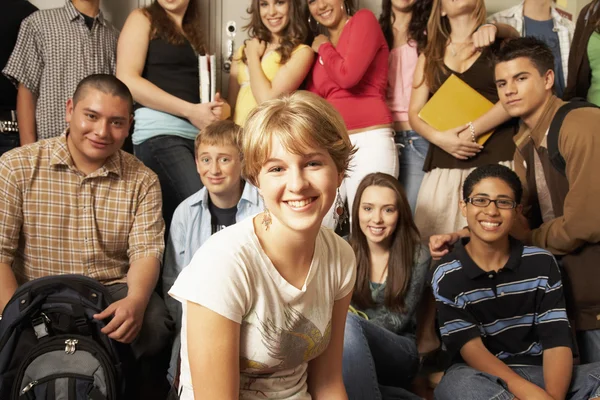 Teenaged girl smiling in front of group of students