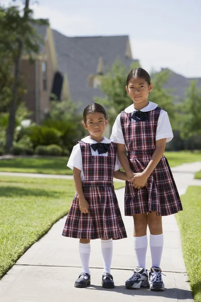 Asian sisters in school uniforms holding hands