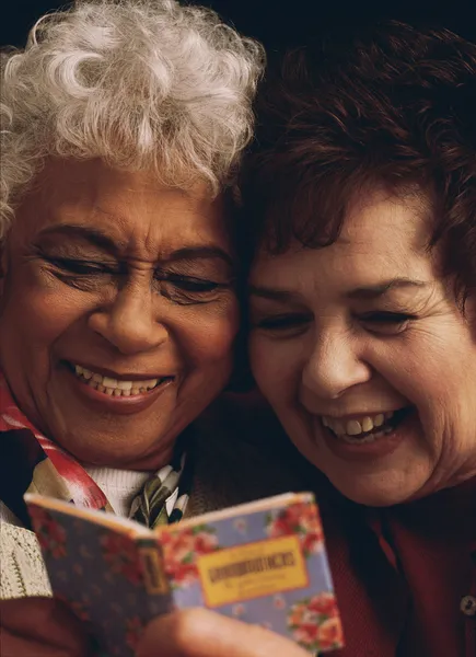 Senior women sharing funny book together