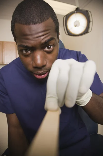 African doctor examining patient with tongue depressor