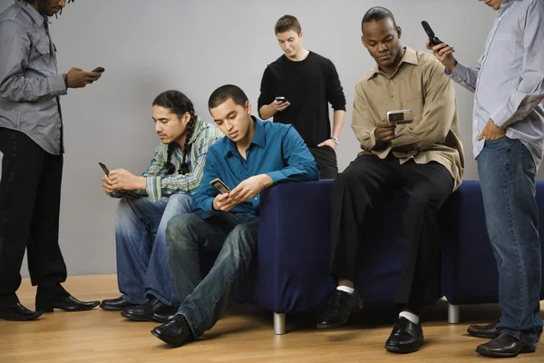 Group of multi-ethnic men text messaging on cell phones