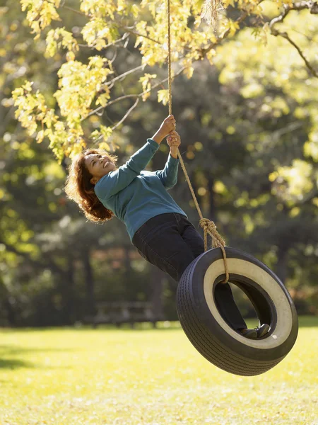 Hispanic woman swinging on tire swing