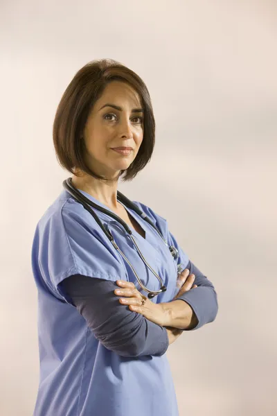 Hispanic surgeon in scrubs with arms crossed