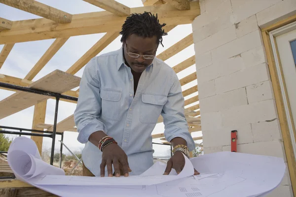 African architect looking at blueprints on construction site