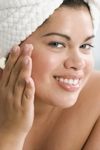 Close up of Hispanic woman applying face lotion