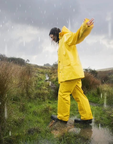 Hispanic woman in rain gear walking in puddle