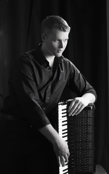 Musician plays the accordion against a dark background