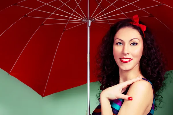 Pin up girl posing with red umbrella