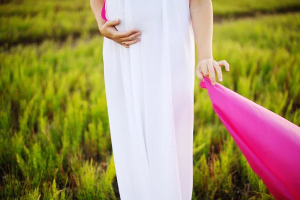 Young caucasian pregnant woman in a white greek dress