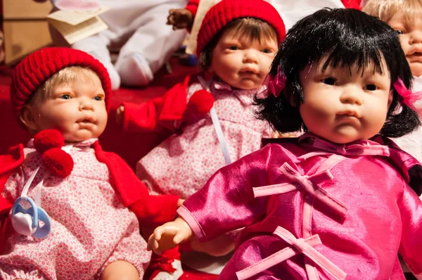 Three baby dolls in colorful clothes.