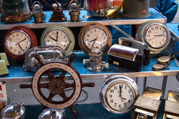 PARIS - JANUARY 13: Old clocks and boat steering wheel for sale at Boulevard de l\'Hopital flea market on January 13, 2013 in Paris, France. This flea market serves the professional antique dealers.