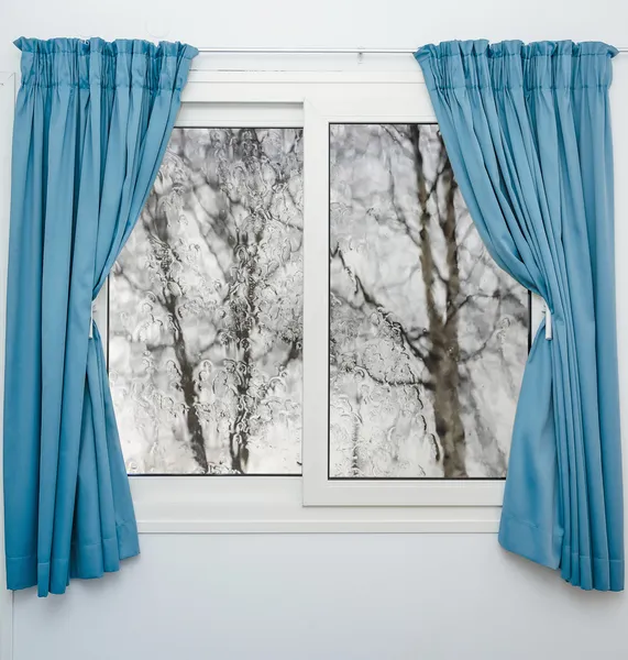 Closed window with curtains in rainy autumn weather