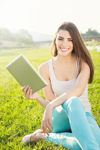 Attractive student in nature holding digital tablet