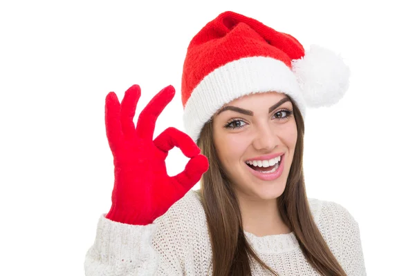 Excited young woman wearing Santa Claus hat gesturing ok