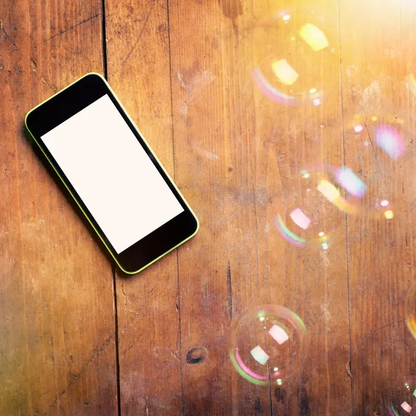 Closeup of smart phone and bubbles on wooden surface