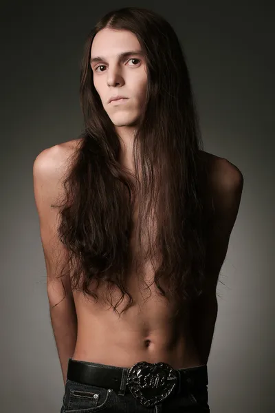 Portrait of a handsome long haired brunet male model over gray b