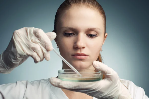 Portrait of young woman - scientist with dropper working at the