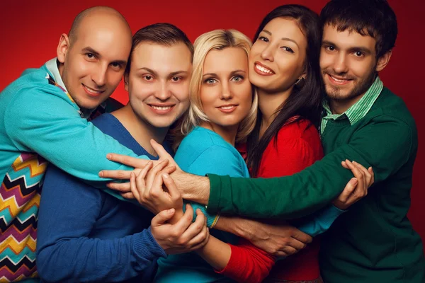 Portrait of five stylish close friends hugging, smiling and posi