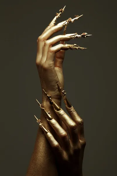 Art Manicure Concept. Beautiful golden hands with golden long ar