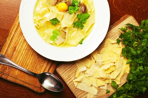 Chicken soup with pasta (noodle) with fresh parsley on a wooden
