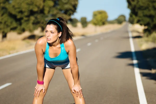 Tired woman sweating after running on road