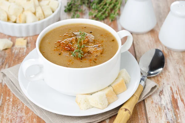 Mushroom cream soup with croutons and thyme in a white bowl