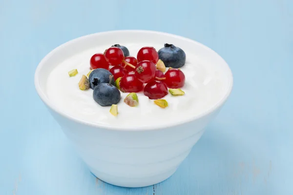 Fresh sweet yogurt with berries and pistachios in a bowl