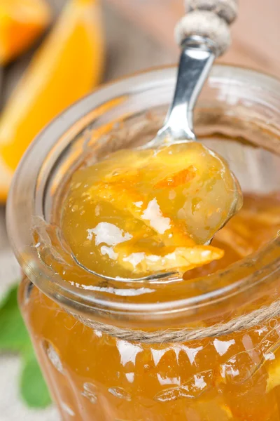 Spoon of orange marmalade in a glass jar