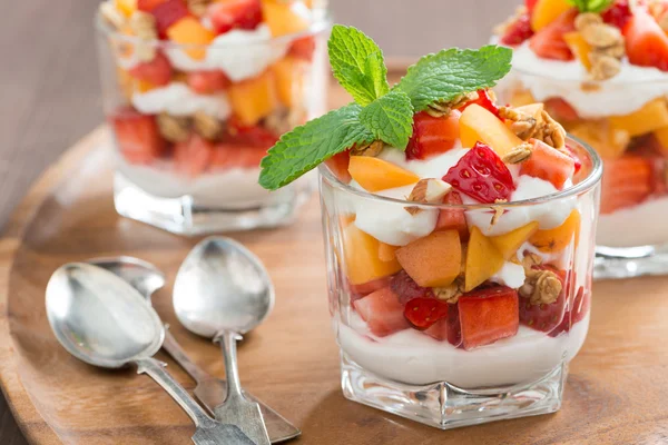 Fruit dessert with whipped cream, mint and granola, close-up