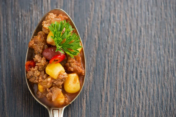 Spicy Mexican dish chili con carne in a spoon