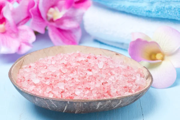 Pink sea salt, flowers and towels, close-up