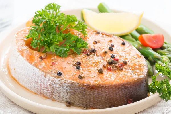 Baked salmon with asparagus and lemon on plate, close-up
