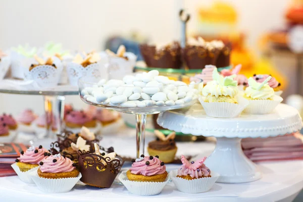 Elegant sweet table with cupcakes, cake pops and candy on dinner