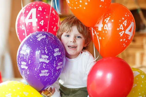 Happy little boy celebrating his 4 birthday with colorful balloo