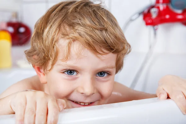 Cute little toddler boy of two years having fun by taking bath i