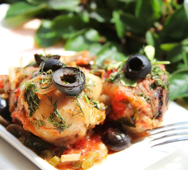 Roasted chicken with black olives, celery, red pepper and tomato sauce in a plate