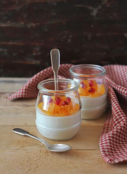 Healthy gluten free panna cotta dessert with pumpkin, persimmon, apricot and pomegranate seeds in jars