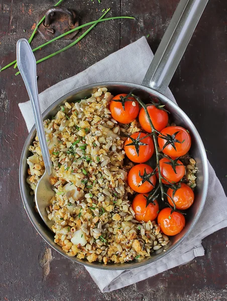 Pie with cod fillet white fish, flax, sunflower seeds, pine nuts, bread crumbs and chopped fresh chives served with roasted cherry tomatoes in a pan