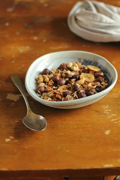 Homemade organic granola with rolled oat flakes, caramelized almonds, cashew, hazelnuts, dried apricots, raisin and dates with banana chips in a breakfast bowl