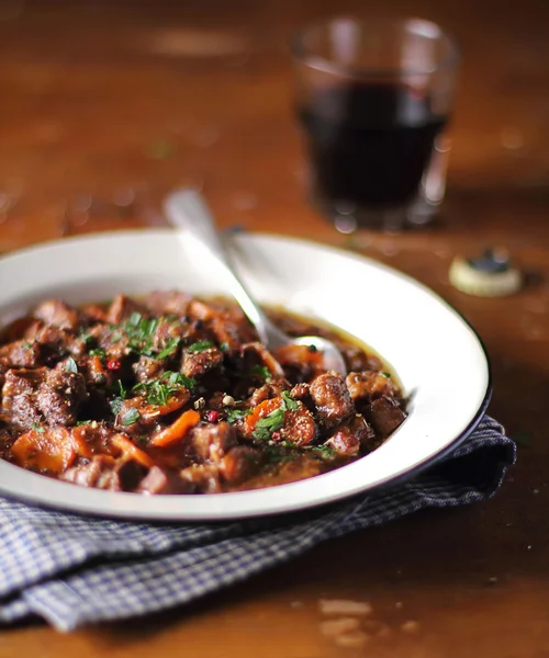 Portion of traditional irish beef and guinness beer stew with carrots and fresh parsley in a plate ready to serve