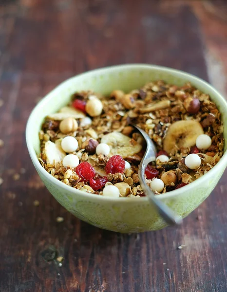 Healthy homemade granola or muesli with toasted oats, dried cherry, cranberry, figs, raisin, hazelnuts, cashew, walnuts, yogurt and white chocolate chips and honey in a bowl for breakfast or snack
