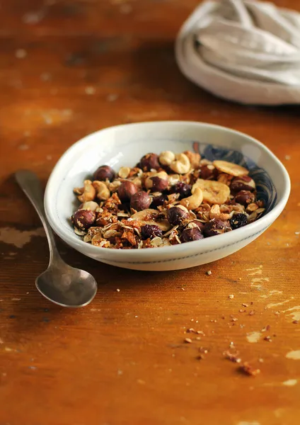 Healthy homemade organic muesli or granola with oats, dried figs, raisin, banana chips and toasted almonds and hazelnuts in a bowl for breakfast or snack