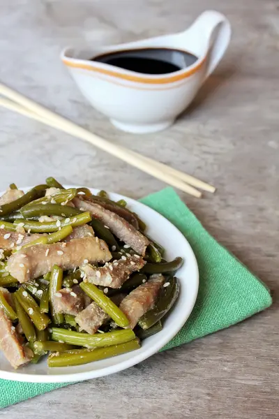 Traditional chinese meal with roasted pork, garlic arrows, beans, ginger and sesame served with sauce