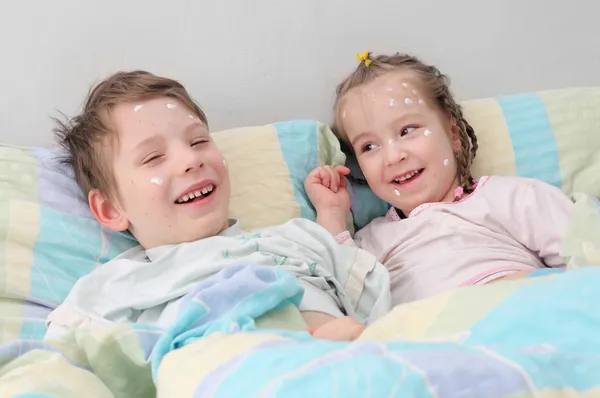 Two diseased children with mosquito bite marks or smallpox in the bed.