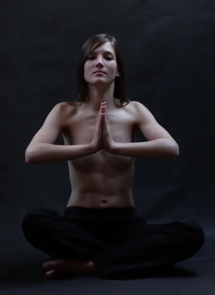 Low key portrait of a young topless beautiful woman in yoga position