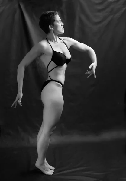 Body builder woman posing on black background.