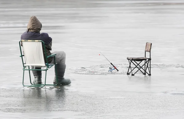 Young fisherman catching a fish on a frozen lake in winter.