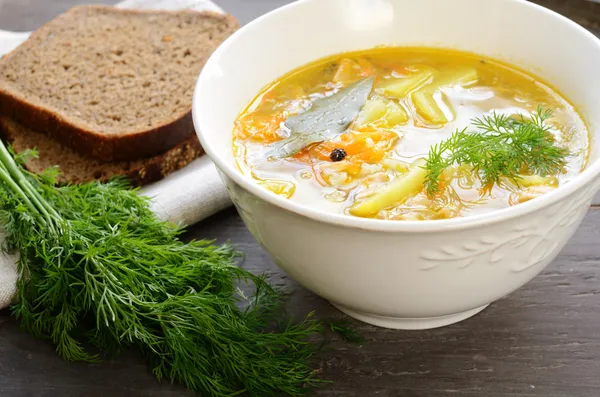Bowl of homemade fish soup served with dark bread and dill